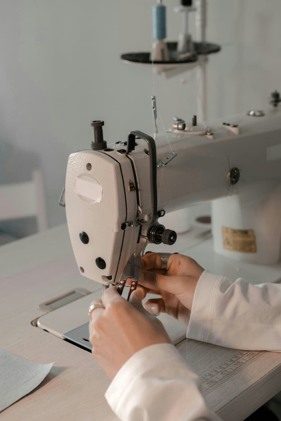 Mãos guiando tecido em máquina de costura reta industrial